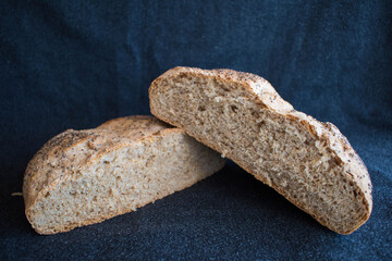 Wholemeal bread with chia seeds. Round bread cut in half with black background