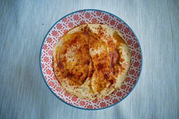 homemade chickpea hummus with red pepper served in a white and red bowl