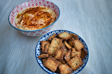 homemade chickpea humus with red pepper and bread sticks crunchy for dipping served in a bowl