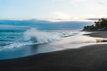 Photo of large waves crashing in sand beach rocks on bali island