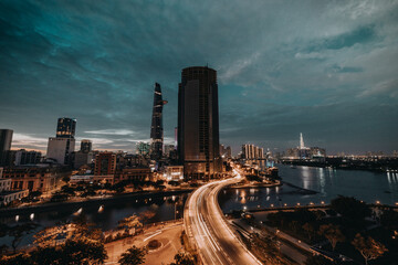 Fototapeta premium Ho Chi Minh city at night, Khanh Hoi bridge, yellow trail on street, the building in picture is bitexco tower, Far away is landmark 81 skyscraper