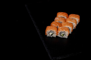 Philadelphia roll with salmon, cheese and cucumber on a black background. Sushi Philadelphia