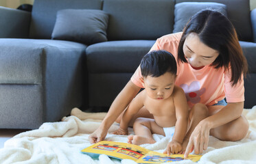 Obraz na płótnie Canvas Asian mom reading book with her son