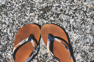 Pair of flip flops with sea rocks n the background. Summer beach vacation concept, getaway. Couples...