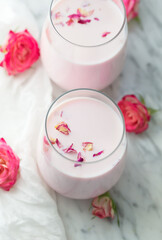 Fototapeta na wymiar Moon milk prepares with pink rose flower. Trendy relaxing bedtime drink form Ayurvedic traditions. Top view, close up