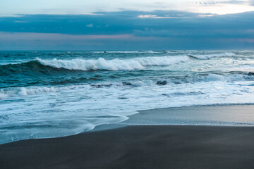 Photo of large waves crashing in sand beach rocks on bali island
