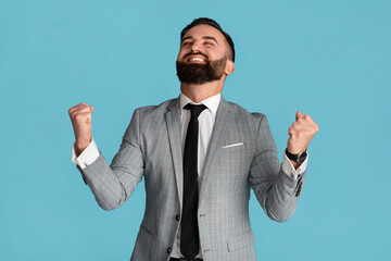 Victory and success. Handsome businessman feeling excited and gesturing YES on blue background