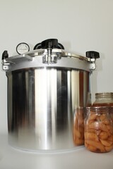 Pressure canner and  jars of preserved food on a white background in vertical format - 362390093