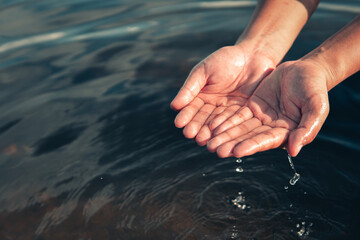 Human hand is touching water on the river,water crisis