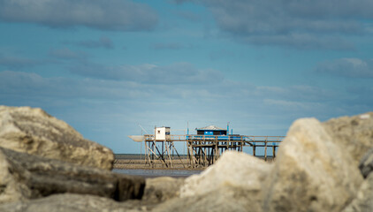 Typical old wooden fishing huts on stilts called carrelet. white rock on foreground