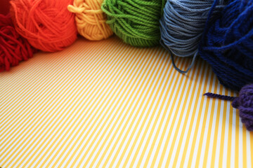 Rainbow color skeins of yarn on a sunny yellow and white background.