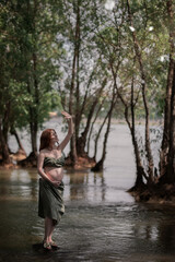 Fototapeta premium red-haired pregnant girl in the forest closes her hand from the sun