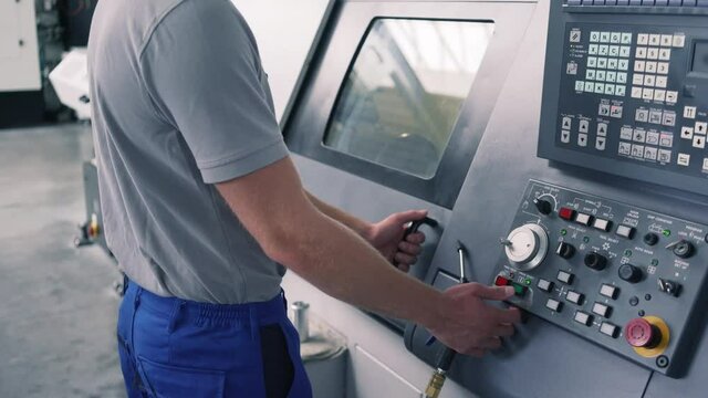 Competent worker operating CNC lathe machine on factory floor