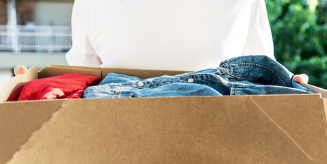 Man holding cardboard box with clothes inside. Concept donation and reuse or recycle your used...