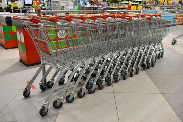 Grocery baskets are at the entrance to the store. Empty baskets in a row, supermarket interior.
