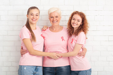 Obraz premium Three Breast Cancer Volunteers Ladies Hugging Over White Background