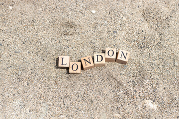 London word on wood cubes . On the beach sand by the sea.