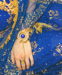 Obraz premium Indian woman cosplay. Young beautiful woman in blue indian sari dress closeup on the multicolored brown background. Body parts