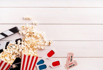 Fototapeta na wymiar movie tickets, clapper board, pop corn and 3d glasses top view on white wooden background with copy space