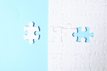 Blank white puzzle with separated piece on light blue background, flat lay