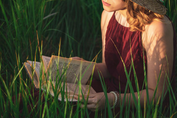 girl reads a book while sitting on green grass