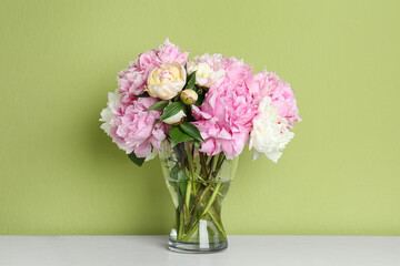 Beautiful peonies on white table against green background