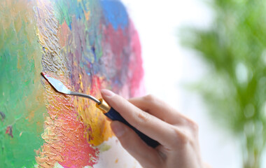 Artist painting on canvas with spatula, closeup
