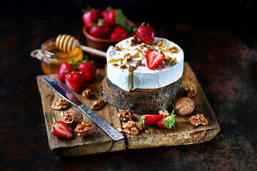 Selective focus. Macro. Composition with Camembert cheese, nuts, strawberries and honey. Luxury...