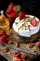 Selective focus. Macro. Composition with Camembert cheese, nuts, strawberries and honey. Luxury...