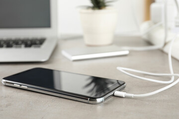 Smartphone charging with cable on light stone table