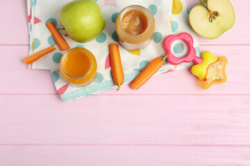 Healthy baby food in jars and fresh ingredients on pink wooden table, flat lay. Space for text
