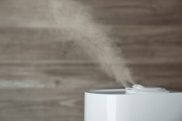 Modern air humidifier on wooden background, closeup. Space for text