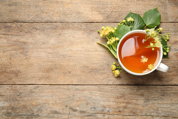 Cup of tea and linden blossom on wooden table, flat lay. Space for text