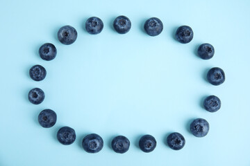 Frame of fresh ripe blueberries on light blue background, flat lay. Space for text