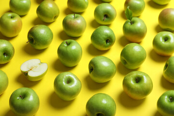 Many tasty green apples on yellow background