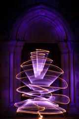 Gothic style sculpture with arch. Curved abstract shape with sparklers. Lightpainting session in night outside. Wooden door with illuminated leds. 