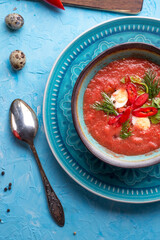  classic spanish raw eating cold soup Gazpacho with quail eggs served at blue  table. flat lay. food recipe. healthy concept.