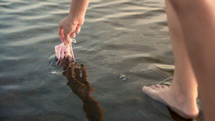 Waste during COVID-19. Woman cleaning up beach. Coronavirus face mask.