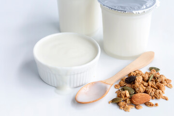 Healthy flavored yogurt in plastic cup and ceramic bowl with granola on white background for organic food healthy with copy space for text.