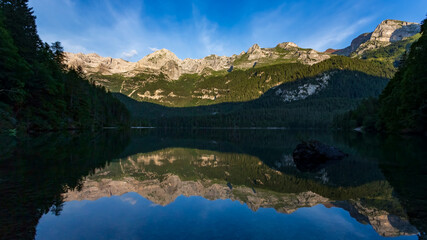 Fototapeta na wymiar Mountains reflected at dawn into Tovel lake water, Italy