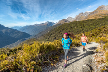 Hiking couple walking on trail at Routeburn Track during sunny day. Male and female hikers are...