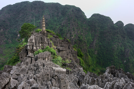 Pagoda on top of a rocky mountain surrounded with luxuriant vegetation in Mua Caves near Nimh Binh