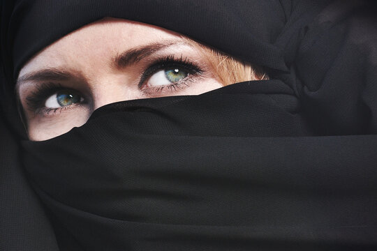 The girl's eyes are in black paranj. Green-blue eyes. Portrait of a blonde woman in a paranj.