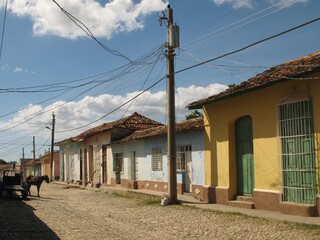 Fototapeta na wymiar Paved street with colorful houses, a horse and an electric pole with many cables, Trinidad, Cuba