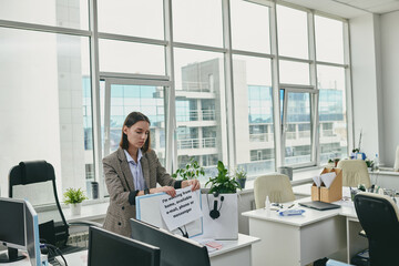 Young elegant secretary putting paper with note about her working from home
