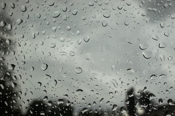 Rain drops on a window glass. Water background. Gray autumn rainy weather. Sadness, melancholy, depression.
