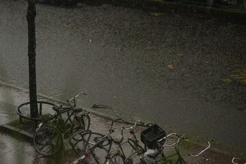 Typical Dutch bicycles under the rain, parked near canal
