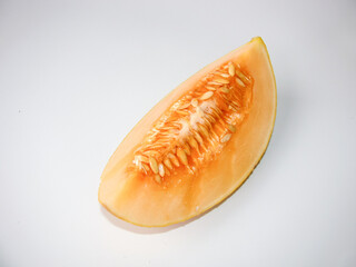 A piece of ripe melon with seeds on a light background.