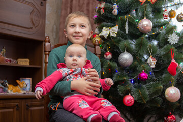 boy with baby sister at the Christmas tree,christmas family portrait of older brother with little sister