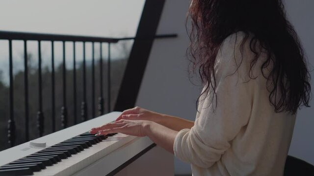 Young girl musisian playing electric piano on balcony